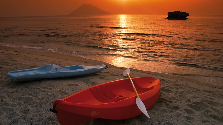 Zwei Paddelboote neben dem Meer mit Sonnenuntergang im Hintergrund