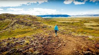 Urlauberin spaziert durch die schier endlos erscheinende natürliche Landschaft Islands