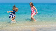 Zwei Kinder spielen und planschen im flachen Teil des Meeres