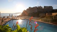 Terrasse mit Pool eines Hotels in Calvi mit Blick aufs Meer und die Festung von Calvi