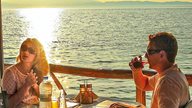 Ein Paar sitzt in einem griechischen Restaurant bei Sonnenuntergang am Meer 